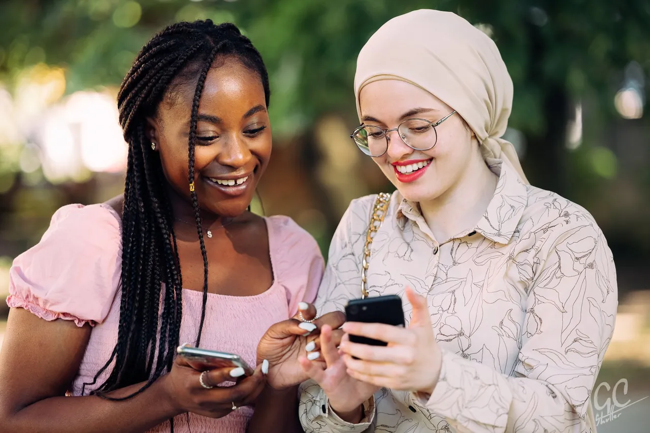 Two friends laughing over their phones, photographed by GCShutter