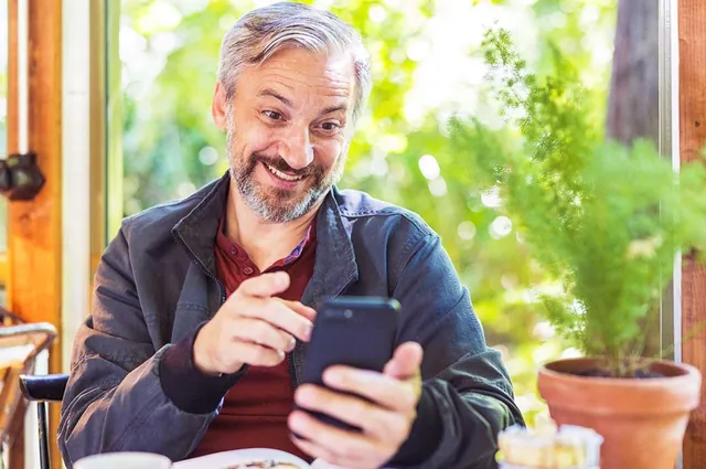 Smiling man using his phone at a cafe, photographed by GCShutter